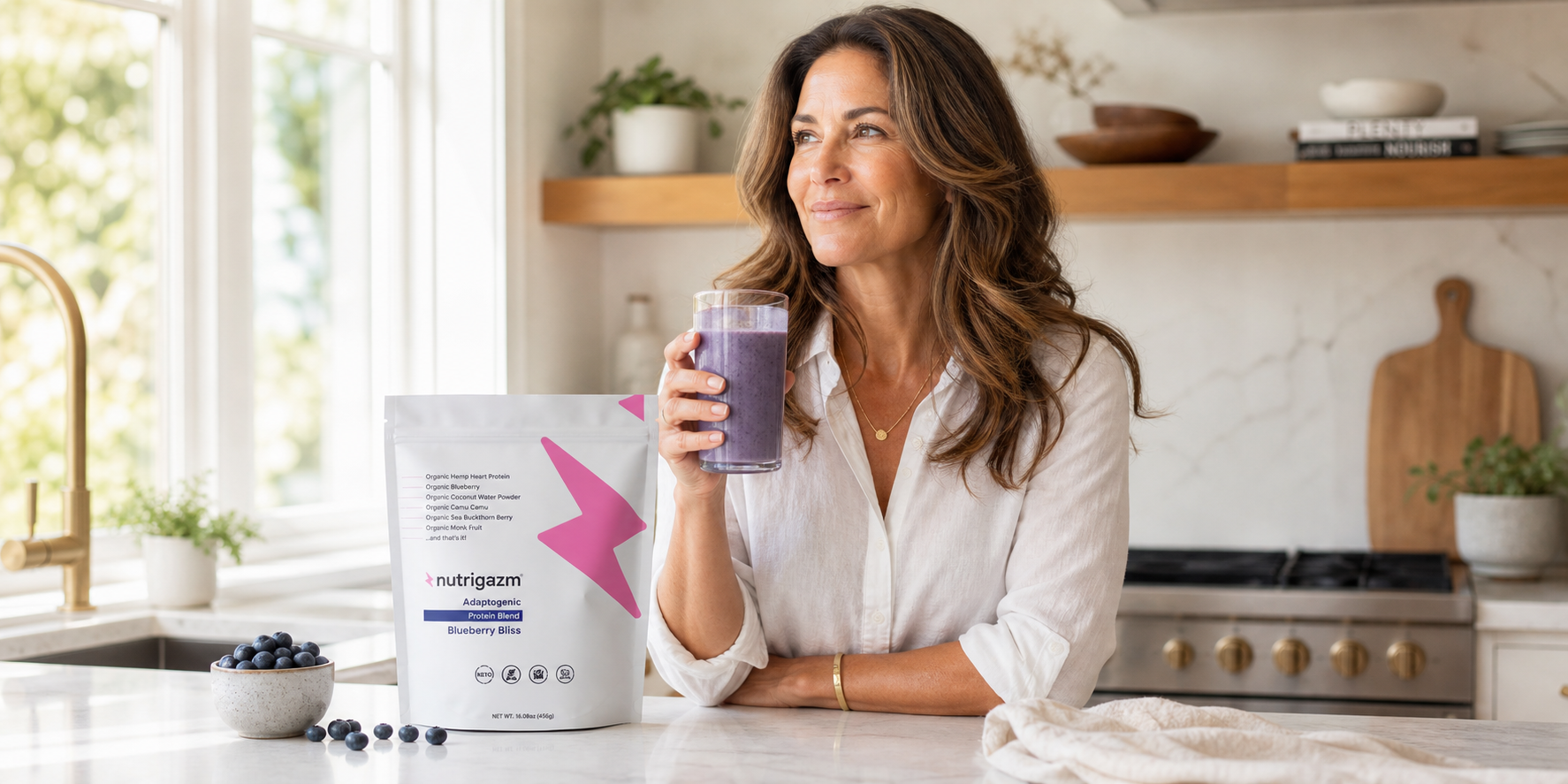 Woman holding a blueberry smoothie beside the Nutrigazm Blueberry Bliss pouch in natural light