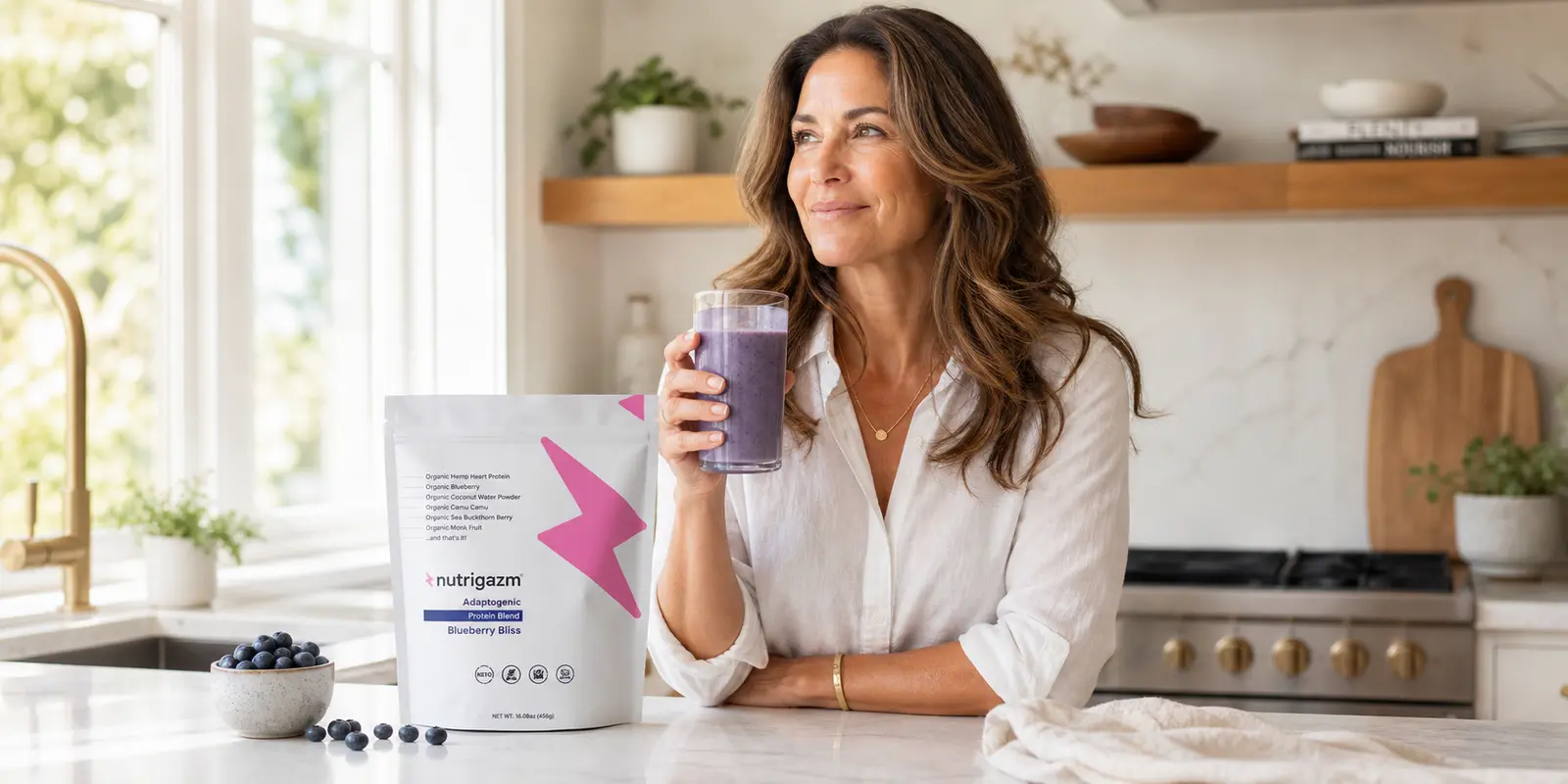 Woman holding a blueberry smoothie in natural kitchen light